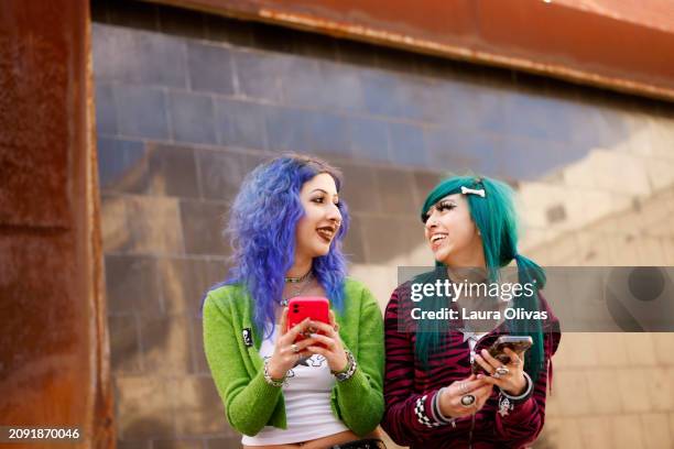 young women smiling while holding phones - eyebrow piercing stock pictures, royalty-free photos & images