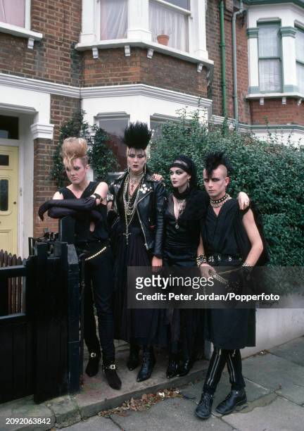 Group of Punks wearing biker jackets and studded belts posing outside their flat in London, circa 1983.