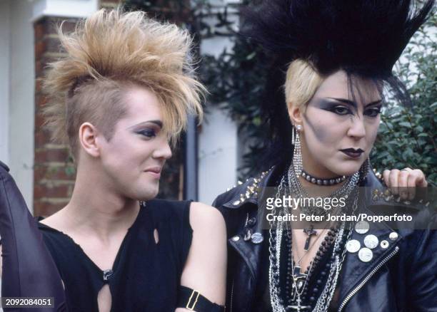 Two Punks wearing distinctive jewellery and hairstyles posing outside their flat in London, circa 1983.
