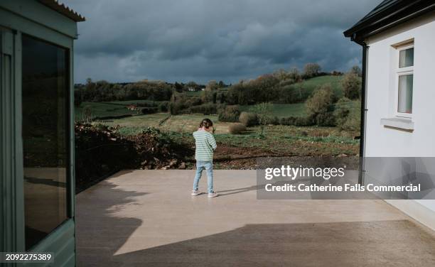 a little girl stands outside, casting a shadow on the concrete - storm clouds sun stock pictures, royalty-free photos & images