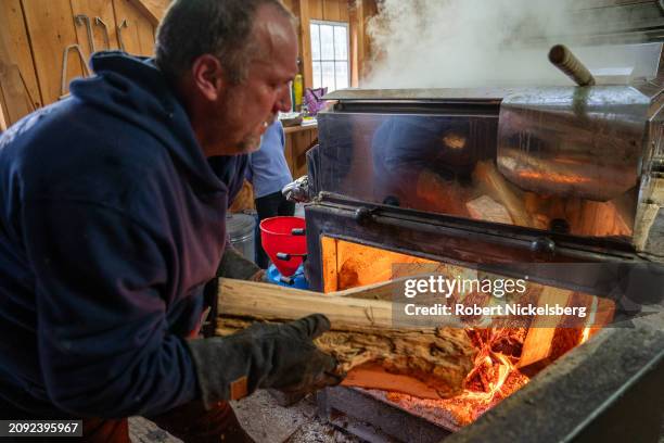 Brian Fortin puts hard wood logs into a firebox that heats an evaporator at Pat LeClaire's sugar house where he assists production March 9, 2024 in...