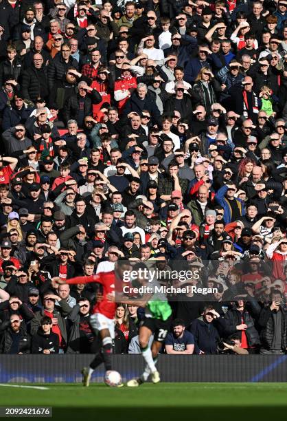 Manchester United fans shield their eyes from the sun as Marcus Rashford of Manchester United battles Jarell Quansah of Liverpool during the Emirates...