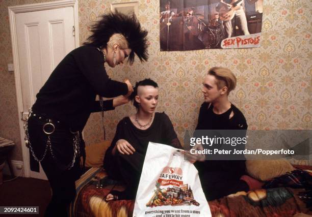 Punk having her head shaved in a bed-sit in London, circa 1983. On the wall is a poster of the Punk band, the Sex Pistols.