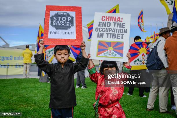 Two kids hold "Stop cultural genocide, free Tibet!" and "China: End the occupation in Tibet" placards during the demonstration. Tibetans, Uyghurs,...