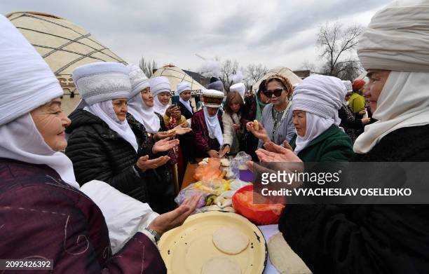 Women wearing traditional costumes pray as they cook during the celebrations of Nowruz in Bishkek on March 20, 2024. Nowruz, "The New Year" in Farsi,...