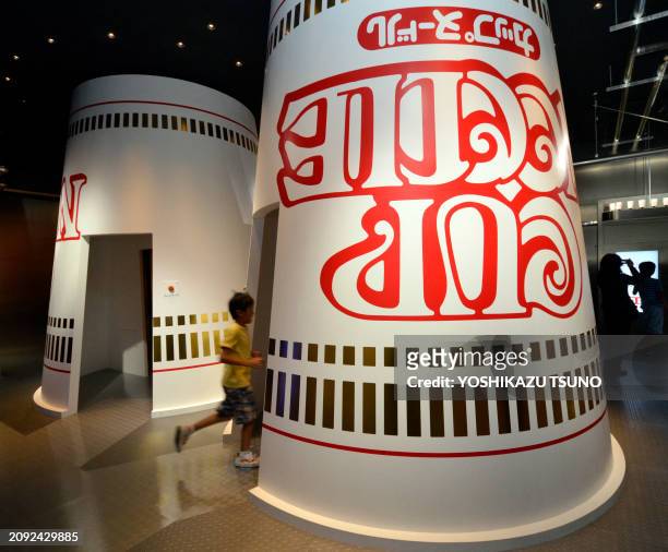 Boy runs inside an exhibit made to look like a giant up-turned cup noodle pot at the opening of a cup noodle museum in Yokohama, suburban Tokyo, on...
