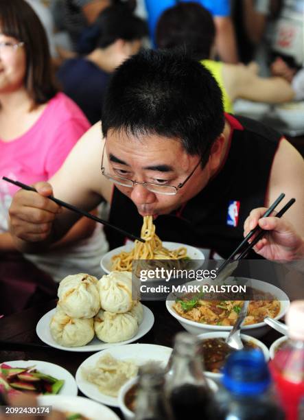 Diner enjoys a bowl of 'Pork Noodles in Brown Bean Sauce' in the crowded the Yaoji Chaogan restaurant, after the restaurant's popularity soared due...