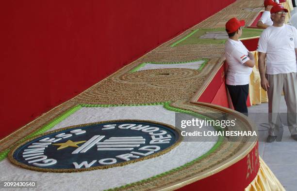 Syrian workers stand next to a mosaic of traditional Arabic sweets, measuring 112 meters long, which entered the Guiness Book of World Records as the...