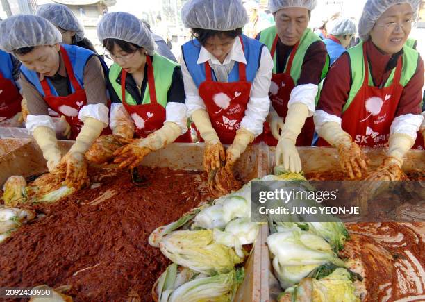 South Korean volunteers make kimchi, the famed national dish of fermented and spiced vegetables, as part of a campaign to help needy people at a...