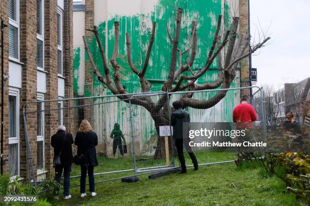 The recent 'Banksy' tree mural is fenced off after the artwork on the side of a building in north London was vandalised with white paint.