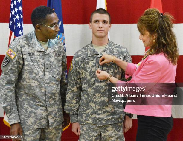 Brigadier General Renwick Payne, left, looks on as Annmarie Peteani of Saratoga Springs pins on a PFC insignia as her son Pvt. Reid Frasier is...