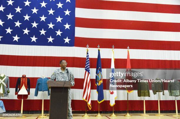 Before a large American flag and a display of historic uniforms, Brigadier General Renwick Payne presides over a traditional ceremony commemorating...