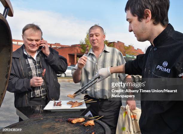 Mezzone Hospitality's Kelmy Tejeda, at right, serves up barbecue to Ian Davies left, and Jimmy Morton of Royal Fireside of Mendon, MA during the...
