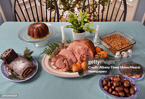 Holiday tablescape including, clockwise from top left, figgy pudding, sweet potato souffl, sticky buns, roasted chestnuts, glazed ham and Buche de...