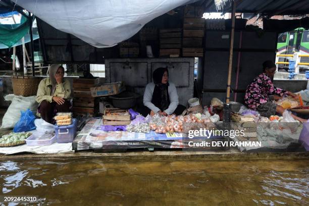 Street vendors sell goods in a flooded street in Kudus, Central Java, on March 20, 2024.