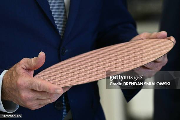 President Joe Biden holds a wafer of chips as he tours the Intel Ocotillo Campus in Chandler, Arizona, on March 20, 2024. The White House unveiled...