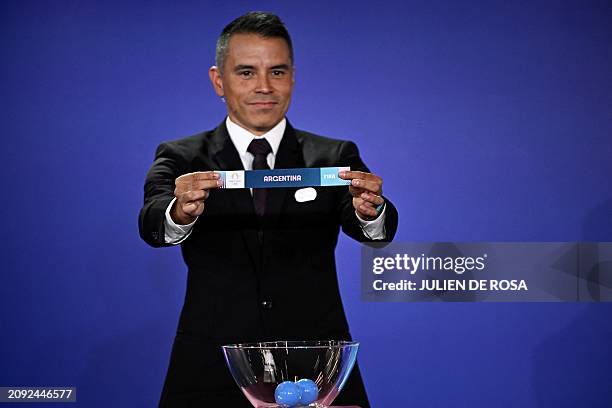 Argentine former football player Javier Saviola holds up the paper slip of Argentina as he proceeds to draw for the Paris 2024 Olympic men football...