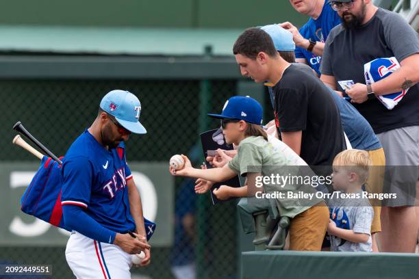 Marcus Semien of the Texas Rangers signs autographs for fans during a spring training game against the San Francisco Giants at Surprise Stadium on...