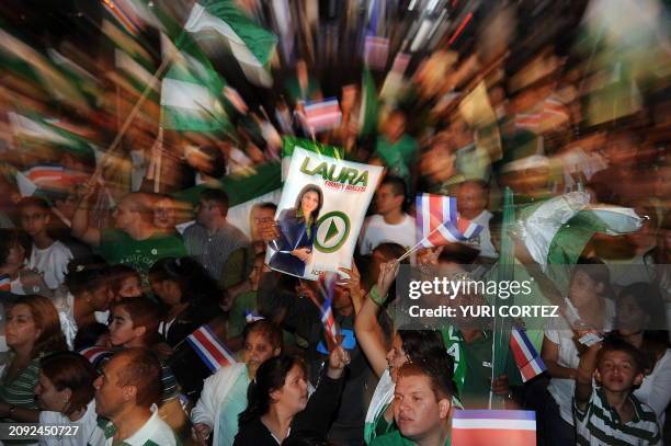 Supporters of Costa Rica's ruling National Liberation Party presidential candidate, Laura Chinchilla, wave flags and hold her campaign poster as they...