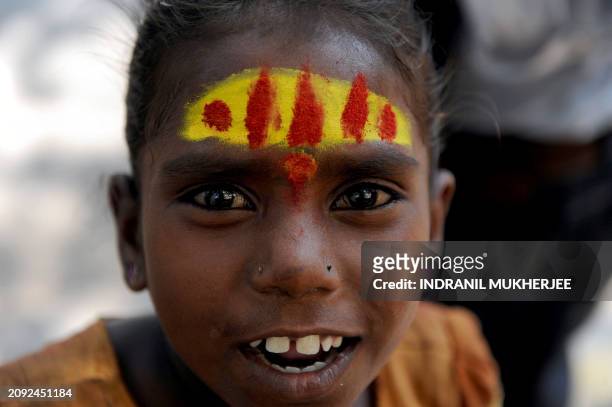 Young Indian child reacts on being photographed as she along with her mother begs for alms while playing a drum on the streets of Mumbai on March 9,...