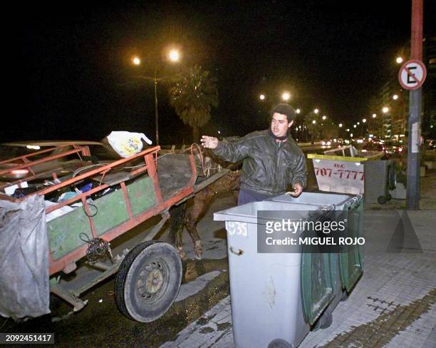 Man sorts through garbage cans in a middle class neighborhood in Montevideo, 02 August 2002. Although this is not an uncommon scene in Urugua, every...
