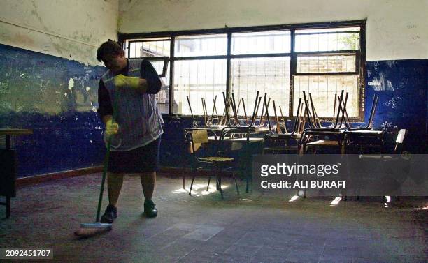 Worker María Ester Lencina sweeps a classroom in Buque Fragata Sarmiento's school, in San Francisco Solano, Argentina 17 April, 2002. Teachers from...