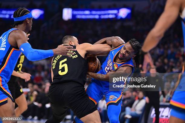 Talen Horton-Tucker of the Utah Jazz and Cason Wallace of the Oklahoma City Thunder wrestle for the ball in the first half at Paycom Center on March...