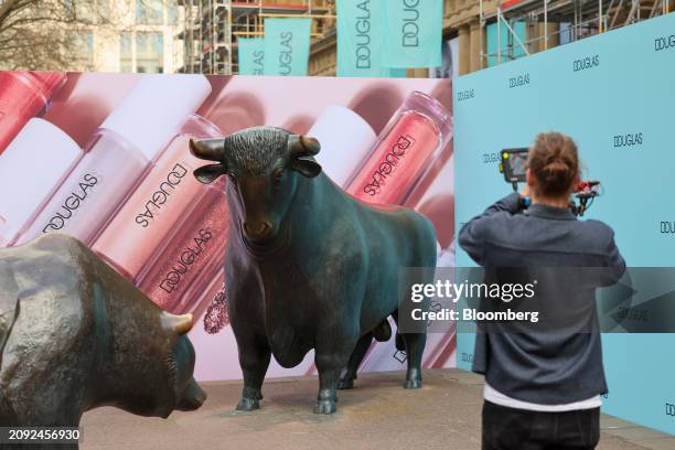 Hoardings featuring the Douglas AG logo near the Bull and Bear statues outside the Frankfurt Stock Exchange, ahead of the company's initial public...