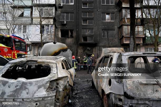 Ukrainian rescuers stand outside of a five-storey residential building after a missile attack, in Kyiv on March 21 amid the Russian invasion in...