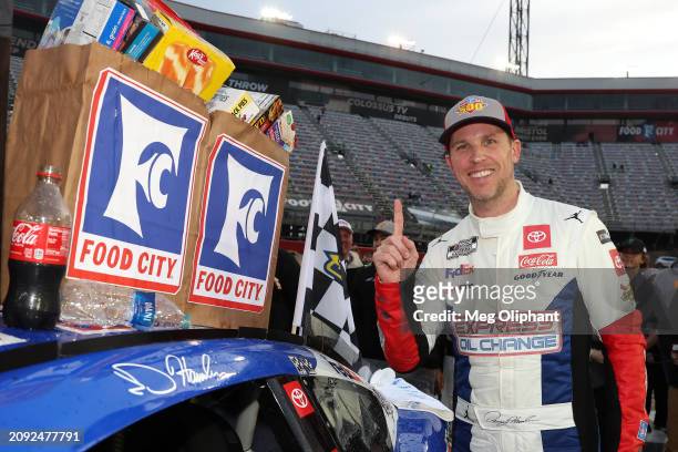 Denny Hamlin, driver of the Express Oil Change Toyota, poses with the winner sticker on his car after winning the NASCAR Cup Series Food City 500 at...