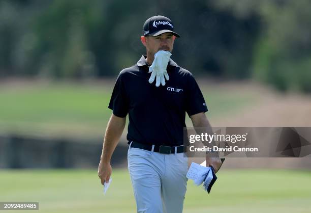 Brian Harman of The United States walks to his second shot on the 10th hole with his golf glove in his mouth during the final round of THE PLAYERS...