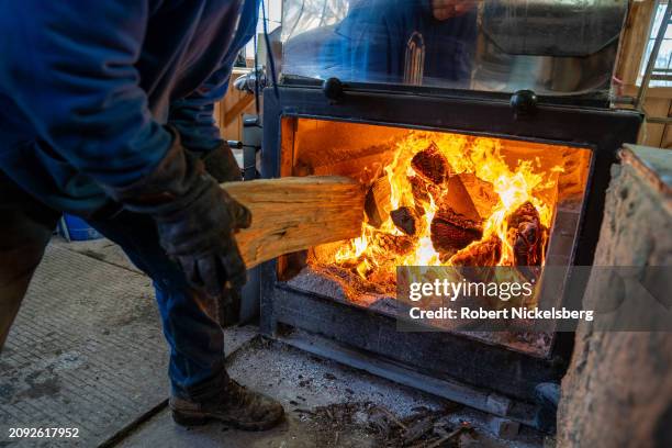 Pat LeClaire loads hard wood logs into the firebox of an evaporator where he boils sap collected from nearby maple trees March 8, 2024 in Charlotte,...