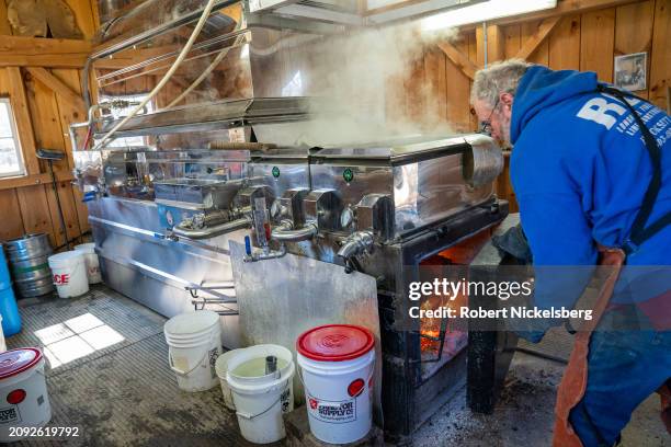 Pat LeClaire loads hard wood logs into the firebox of an evaporator where he boils sap collected from nearby maple trees March 8, 2024 in Charlotte,...