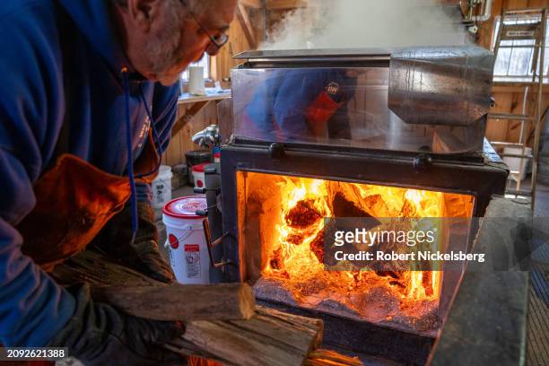 Pat LeClaire loads hard wood logs into the firebox of an evaporator where he boils sap collected from nearby maple trees March 8, 2024 in Charlotte,...