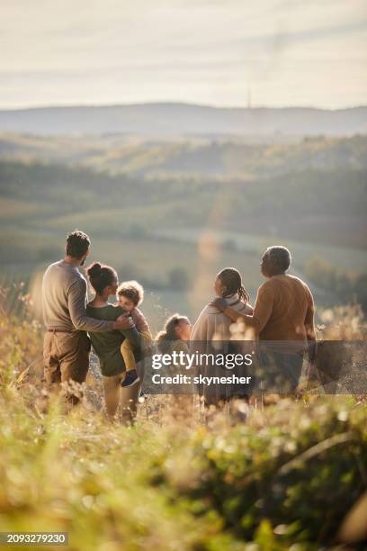 rückansicht einer glücklichen schwarzen großfamilie, die sich an einem herbsttag auf einem hügel unterhält. - familie mit mehreren generationen stock-fotos und bilder