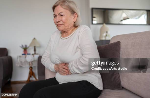 seniorin mit bauchschmerzen - symptom stock-fotos und bilder
