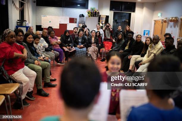 Members of the Baha'i faith and guests from other religions watch children perform a play as they come together in the Ida Kinsey Centre to celebrate...