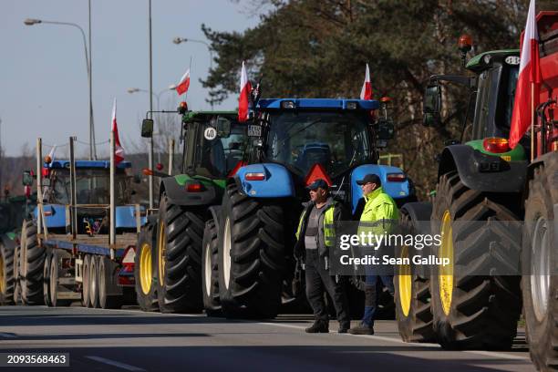 Farmers stand with Polish flags and their tractors while blocking the A12 highway border crossing to Germany on March 18, 2024 near Slubice, Poland....