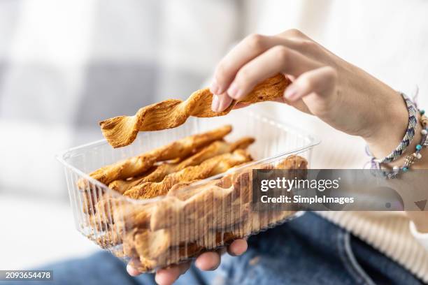 a young woman's hands hold a plastic package with crispy puff pastry sticks. - savoury food stock pictures, royalty-free photos & images