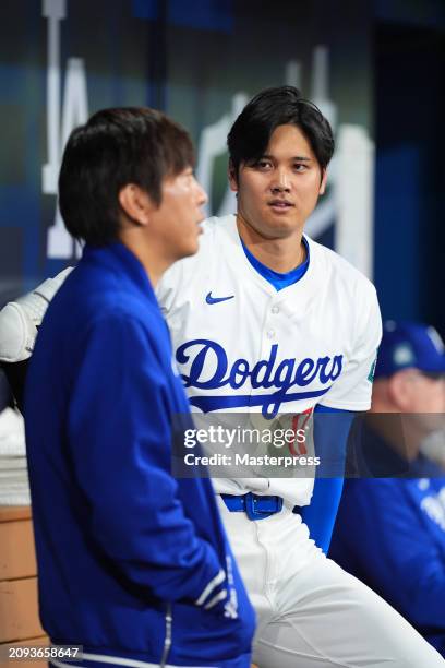 Shohei Ohtani of the Los Angeles Dodgers talks with interpreter Ippei Mizuhara during the exhibition game between Team Korea and Los Angeles Dodgers...