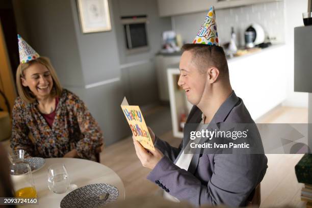 happy man with down syndrome reading birthday card at home. - man reading card stock pictures, royalty-free photos & images