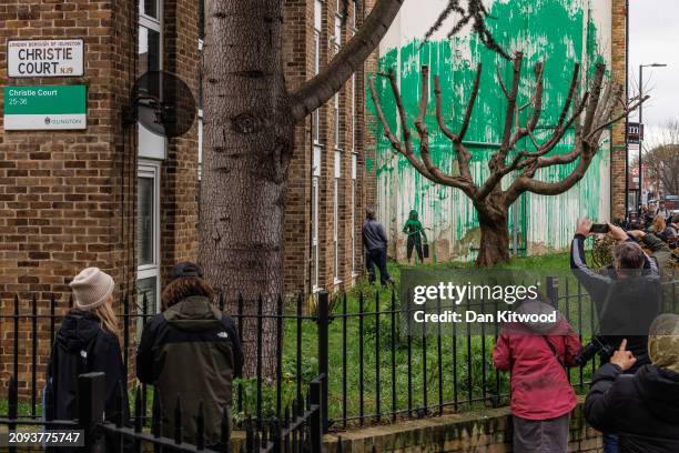 Members of the public photograph a recent mural which has appeared on the side of a building in Islington on March 18, 2024 in London, England. The...