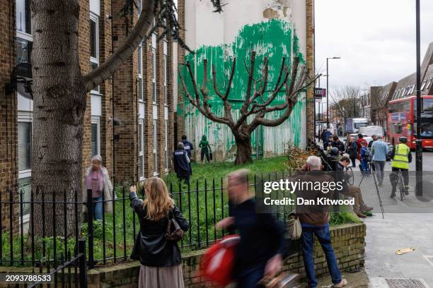 Members of the public photograph a recent mural which has appeared on the side of a building in Islington on March 18, 2024 in London, England. The...