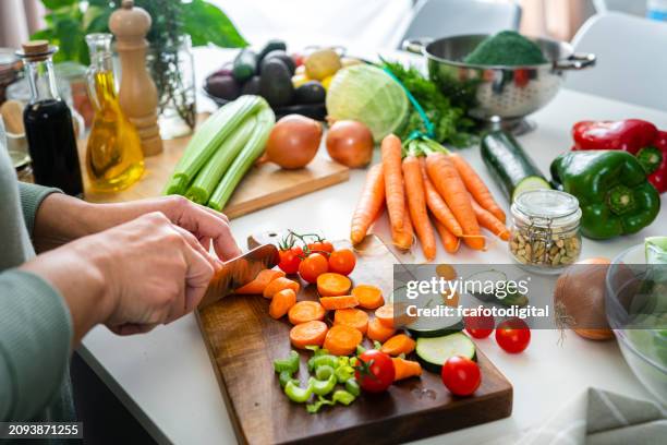 nahaufnahme von frauenhänden, die frische bio-karotten auf der küchentheke schneiden - gesunde ernährung stock-fotos und bilder