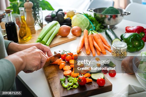 Close up of woman's hands slicing fresh organic carrots on kitchen counter Close up of woman's hands slicing fresh organic carrots on kitchen counter