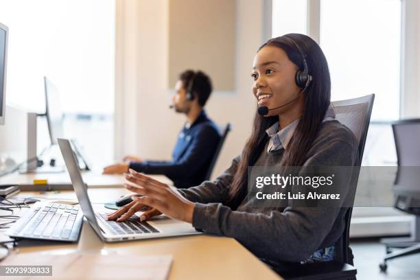 customer service representative fielding phone calls in office - gestione delle relazioni con i clienti foto e immagini stock
