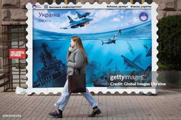 People walk past a poster-size stamp installed in the city centre and depicting Russian warships sunk after Ukrainian attacks in the Black Sea on...
