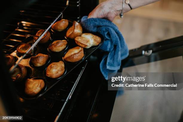 a person removes a tray full of crispy yorkshire puddings from an oven - baking pan stock pictures, royalty-free photos & images