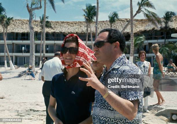 Former First Lady Jacqueline Kennedy , wearing sunglasses and a headscarf, talks to an unidentified guide at a beach on Cozumel island, Mexico, March...