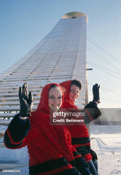 Two Olympic hostesses wave from the bottom of the steps leading up to the Olympic cauldron ahead of the Winter Olympics' opening ceremony in...